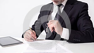 Real estate agent holding out house keys to client and signing mortgage papers