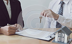 Real estate agent holds the keys to send to the client and offers the conditions for signing the house sale agreement and home ins