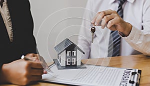 Real estate agent holds the keys to send to the client and offers the conditions for signing the house sale agreement and home ins