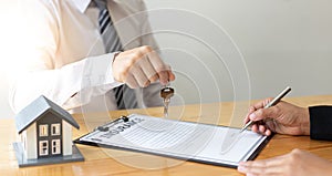 Real estate agent holds the keys to send to the client and offers the conditions for signing the house sale agreement and home ins