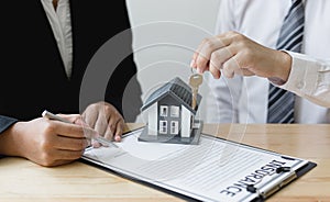 Real estate agent holds the keys to send to the client and offers the conditions for signing the house sale agreement and home ins