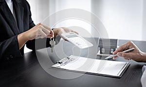 Real estate agent holds the keys to send to the client and offers the conditions for signing the house sale agreement and home ins