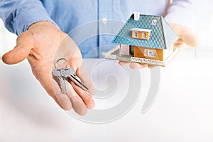 Real estate agent with house model and keys in hands