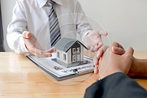 A real estate agent with House model is talking to clients about buying home insurance. Home insurance concept