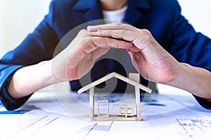 Real estate agent or Insurance agent making gestures to protect house model. Property housing insurance protection concept