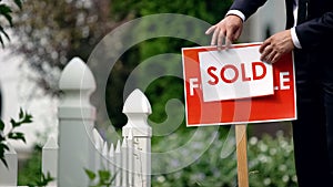 Real estate agent puts sold inscription on for sale signboard, successful deal