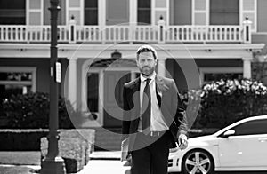 Real estate. Agent ready to sell home. Businessman standing outside a modern house. Dream home.