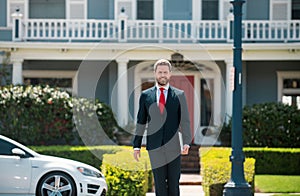 Real estate. Agent ready to sell home. Businessman standing outside a modern house.