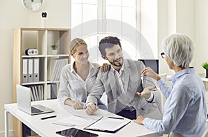 Real estate agent or realtor gives the key to new property to a happy young couple