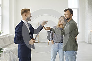 Real estate agent or realtor gives keys to new house or apartment to young couple