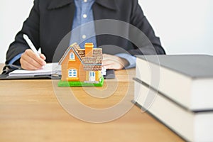 real estate agent realtor writing note with house model. buying