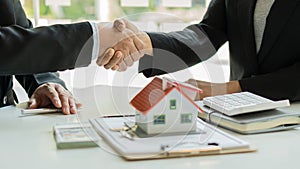 Real estate agent shakes hands with client after signing home purchase agreement after Finan has passed. photo
