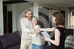 Real estate agent shaking hands couple clients in rental house