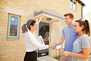 Real estate agent shaking hands with new property owners photo