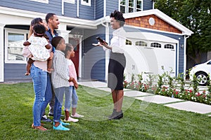 Real estate agent showing a family a house photo