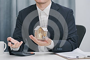 Real estate agent showing house model at office. Home sales and home insurance concept.