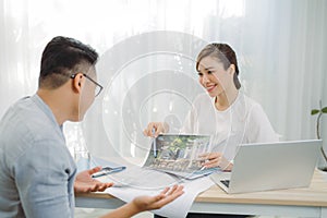 Real-estate agent showing house plans for client at office