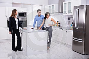 Real Estate Agent Showing Refrigerator In House To A Couple