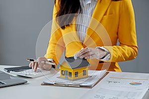 A real estate agent sits in her office, The salesperson is presenting what the home the customer is about to buy looks like, The