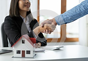 Real estate agents and customers shake hands to congratulate on signing a contract to buy a house with land and