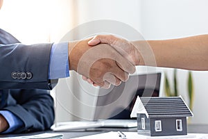 Real estate agents and customers shake hands to congratulate on signing a contract to buy a house with land and insurance