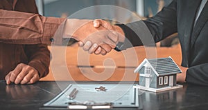 Real estate agents and customers shake hands to congratulate on signing a contract to buy a house with land and insurance