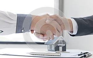Real estate agents and customers shake hands to congratulate on signing a contract to buy a house with land and insurance