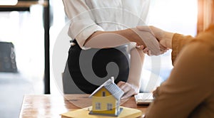 Real estate agents and customers shake hands to congratulate on signing a contract to buy a house with land and insurance,