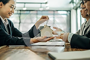 Real estate agents holding model house and keys for submit documents for customers to sign for a sale contract,real estate concept