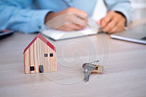 Real estate agents or home sales agents concept. House keys and house models are placed on the desk. Customers are about to sign r