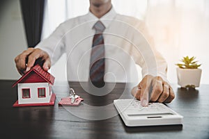 Real estate agents offer contracts to purchase or rent residential. Business person hands holding home model, small building red