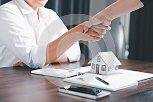 Real estate agents offer contracts to purchase or rent residential. Business person hands holding home model, small building red