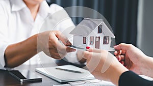 Real estate agents offer contracts to purchase or rent residential. Business person hands holding home model, small building red