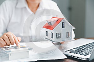 Real estate agents offer contracts to purchase or rent residential. Business person hands holding home model, small building red