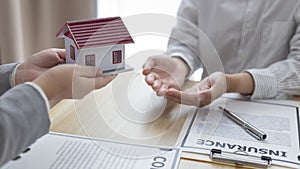 Real estate agents or sales managers hand over homes to customers who have signed home purchases with insurance