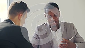 Real-estate black agent with man signing contract in white office