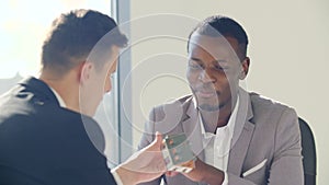 Real-estate black agent with man signing contract in white office