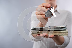 Real estate broker agent keeps key and home shaped keychain above mortgage loan agreement application on white background. Concept