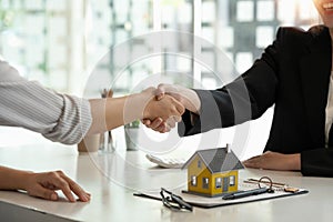 Real estate broker and customer shaking hands after signing a contract: real estate, home loan and insurance concept