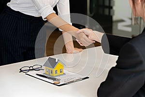 Real estate broker and customer shaking hands after signing a contract: real estate, home loan and insurance concept