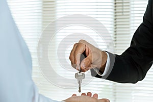 Real estate broker manager giving house key to customer after signing contract for buying house in estate agent office