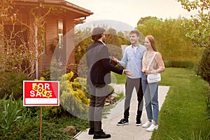 Real estate broker and new home owners in front of their property outdoors