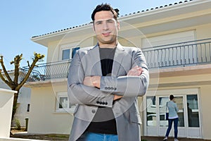 Real estate broker posing outside house