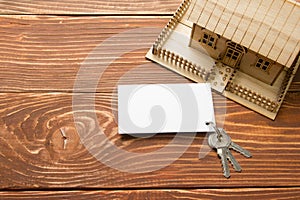 Real Estate Concept. Model house, keys, blank business card on wooden table. Top view. Toned image