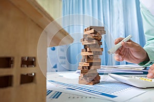 Real estate concept, prevent consultant urgent, wood toy building on business desk table in office.