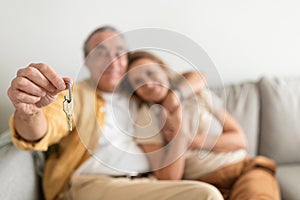 Real estate concept. Senior couple holding home keys, embracing, celebrating buying property, selective focus