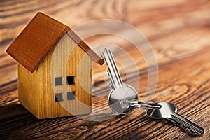 Real estate concept with small toy wooden house and key on wooden background. Idea for real estate concept, personal property an