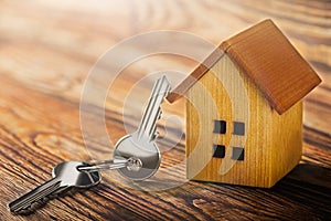 Real estate concept with small toy wooden house and key on wooden background. Idea for real estate concept, personal property an