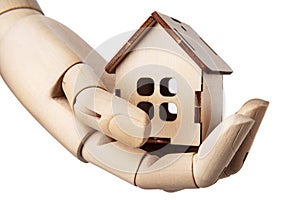 Real estate concept. Wooden doll& x27;s hand holds a wooden toy house isolated on white.