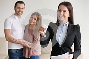 Real estate deal. Female smiling realtor showing keys to flat